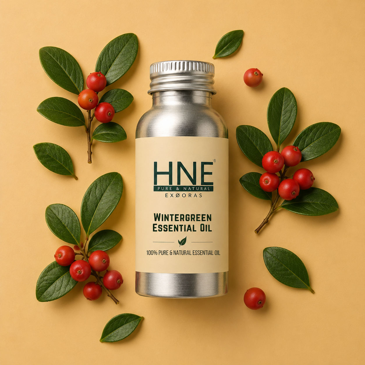 Silver bottle of HNE Wintergreen Essential Oil with green leaves and red berries on a beige background